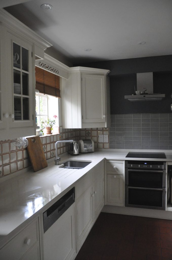 Kitchen kitchen cupboards and walls painted in an off white and feature wall painted in a dark grey